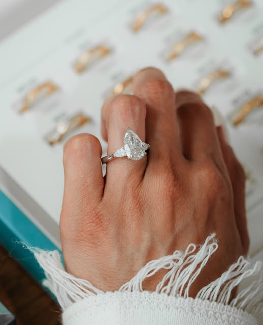 Verlobungsring mit Tropfen-Diamant an der Hand
